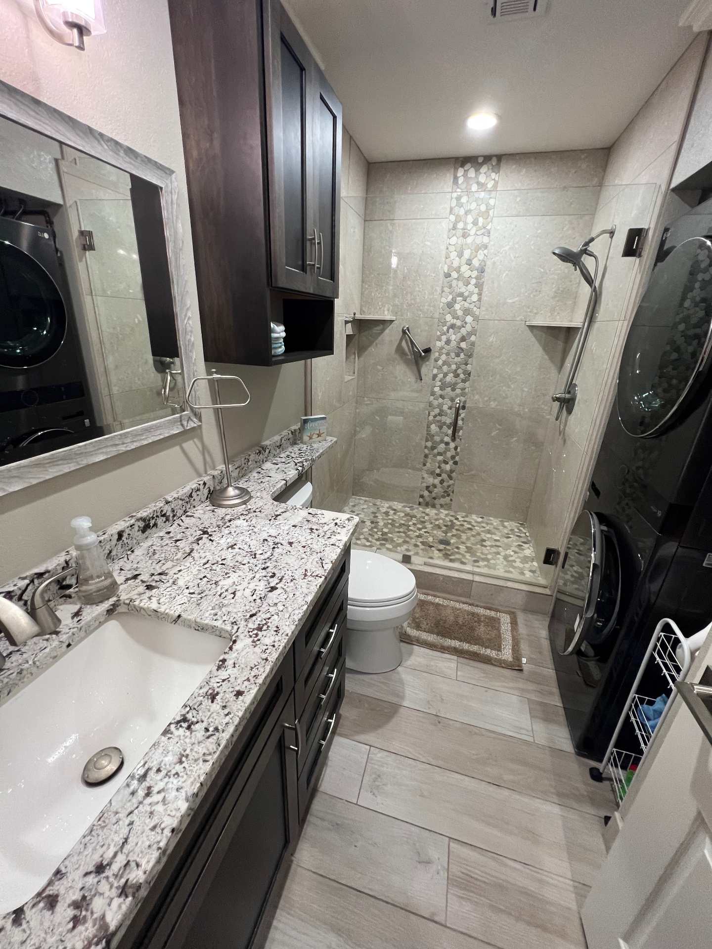 Stone walk-in shower with stacked laundry